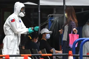 Một binh sĩ mặc đồ bảo hộ phun thuốc khử trùng trước khi người dân rời khỏi một điểm xét nghiệm COVID-19 ở TP Đài Bắc (Đài Loan). Ảnh: REUTERS