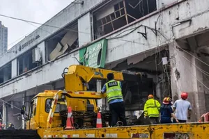 Nhân viên cứu hộ tìm cách trèo qua các tấm bê tông vỡ nát để tiếp cận những người mắc kẹt bên trong.