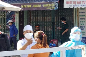 Nhân viên y tế đo thân nhiệt cho bệnh nhân chạy thận tại chốt phong tỏa Bệnh viện Đà Nẵng. Ảnh: TÂM AN