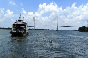 Những chuyến phà của Cụm phà Vàm Cống vẫn miệt mài qua lại đôi bờ, còn phía xa cầu Vàm Cống đã hoàn tất chờ ngày thông xe. Ảnh HOÀNG THỊ)