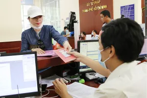 Từ ngày 1-7, cơ quan công an sẽ không cấp mới sổ hộ khẩu giấy mà chuyển sang quản lý bằng cơ sở dữ liệu về cư trú. Trong ảnh: Người dân xuất trình sổ hộ khẩu khi làm thủ tục tại Sở Tư pháp TP.HCM. Ảnh: HOÀNG GIANG