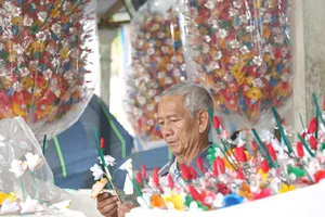 Ông Nguyễn Hóa đang tỉ mỉ làm ra những bông hoa giấy. Ảnh: N.DO