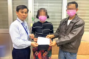 Anh Lê Minh Hiển (trái) trao danh sách mạnh thường quân hỗ trợ viện phí cho vợ chồng ông M, môt trong những bệnh nhân nghèo đang chữa trị tại BV. Ảnh: TRẦN NGỌC 