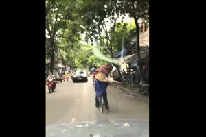 Vừa đạp xe vừa vác thang giữa nơi đông người
