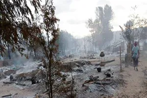 Một người dân đi ngang qua đống đổ nát sau vụ cháy do quân đội Myanmar gây ra. Ảnh: AP