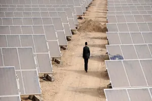 Một người đàn ông đang đi giữa các tấm pin mặt trời ở thành phố Aksu,Tân Cương, Trung Quốc. Ảnh: REUTERS