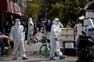 Nhân viên cảnh sát TP Thượng Hải mặc đồ bảo hộ tiến hành phong tỏa các cửa hàng thực phẩm sau đợt bùng dịch hôm 29-3. Ảnh: REUTERS