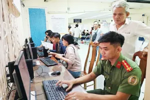Người dân được cán bộ công an hỗ trợ làm tờ khai cấp hộ chiếu phổ thông. Ảnh: NGUYỄN TÂN