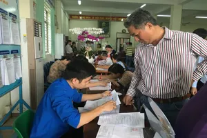 Cán bộ hướng dẫn người dân làm hồ sơ cấp giấy chứng nhận. Ảnh VIỆT HOA