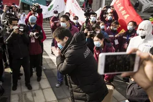 Một bệnh nhân hồi phục xuất viện ở Vũ Hán (Trung Quốc) chắp tay cám ơn các bác sĩ cứu chữa cho mình. Ảnh: SCMP