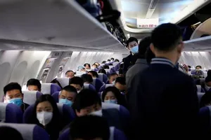 Hành khách đeo khẩu trang trên một máy bay của hãng Shanghai Airlines tại sân bay quốc tế ở Thượng Hải (Trung Quốc) ngày 25-3. Ảnh: REUTERS