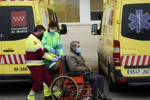 Nhân viên y tế di chuyển một bệnh nhân trên xe lăn tại một bệnh viện ở Madrid (Tây Ban Nha) ngày 30-3. Ảnh: REUTERS