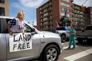 Nam y tá đứng ở vạch đi bộ chặn dòng xe người biểu tình phản đối lệnh đóng cửa vì COVID-19, tại TP Denver, bang Colorado (Mỹ). Ảnh: ALYSON MCCLARAN 