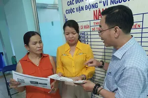 Bà Nguyễn Thị Nhẫn (giữa), Bí thư Đảng ủy phường 13, quận 3, TP.HCM, hướng dẫn người dân sử dụng Cổng thông tin danh sách cử tri quận 3. Ảnh: V.HOA