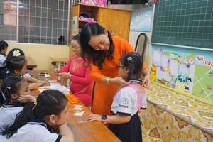 Học sinh lớp 1 trường tiểu học Trần Quốc Thảo, quận 3 được giáo viên ân cần đeo bảng tên. Ảnh: NGUYỄN QUYÊN