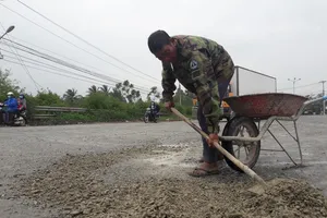 Người đàn ông chở đá vá ổ gà trên quốc lộ 
