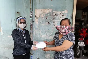 Bà Triệu Thị Bích Huyền (trái), Phó chủ tịch UBND phường 11, quận Bình Thạnh trao tiền hỗ trợ cho người dân. Ảnh: NGUYỄN HIỀN