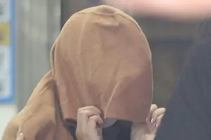 Một phụ nữ, được cho là mẹ của hai thi thể trẻ em được tìm thấy trong vali ở New Zealand vào tháng trước, bị áp giải đến văn phòng công tố ở thành phố Ulsan (Hàn Quốc) ngày 15-9. Ảnh: REUTERS