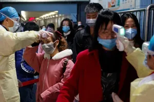 Nhân viên y tế kiểm tra thân nhiệt hành khách đi tàu ở Trung Quốc.