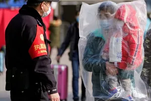 Hành khách đeo khẩu trang và cả túi nhựa tại ga tàu lửa Thượng Hải, Trung Quốc.