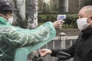 Một nhân viên bảo vệ đo thân nhiệt một người đàn ông tại khu chợ ở Thượng Hải, Trung Quốc.