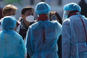 Nhân viên mặc đồ bảo hộ đo thân nhiệt hành khách trước khi họ lên xe buýt gần du thuyền Diamond Princess bị cách ly tại cảng Yokohama, Nhật Bản.