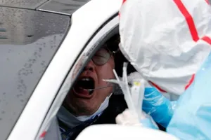 Một nhân viên y tế mặc đồ bảo hộ dùng tăm bông lấy mẫu từ một du khách tại trung tâm xét nghiệm ở Daegu, Hàn Quốc.