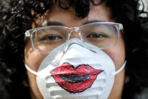 Một đàn ông đeo khẩu trang khi chúc mừng ngày Quốc tế phụ nữ 8-3 ở Kuala Lumpur (Malaysia). Ảnh: REUTERS