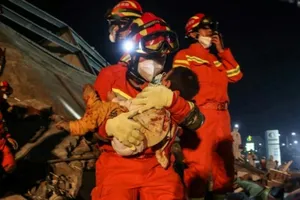 Lực lượng cứu hộ giải cứu một trẻ em mắc kẹt trong đống đổ nát của khách sạn Xinjia. Ảnh: AFP