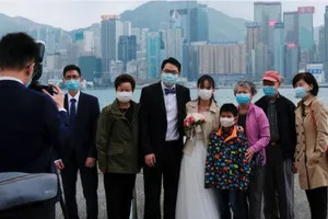 Một cặp vợ chồng mới cưới cùng người thân đeo khẩu trang chụp ảnh tại Tsim Sha Tsui (Hong Kong). Ảnh: REUTERS 