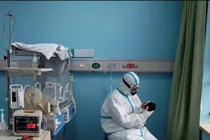 Một nữ y tá bế một đứa trẻ sơ sinh bị nhiễm COVID-19 tại một bệnh viện ở Vũ Hán. Ảnh: REUTERS