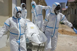 Nhân viên y tế mặc đồ bảo hộ khiêng một thi thể nạn nhân COVID-19 ở Mogadishu, Somalia. Ảnh: AP