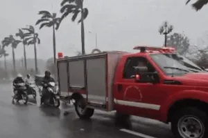 Xe chữa cháy che chắn cho hàng chục phương tiện đi qua cầu vượt trong cơn mưa bão ở Hà Nội