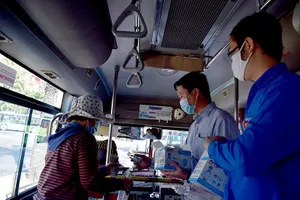 Phát khẩu trang và nước rửa tay miễn phí cho người đi xe buýt