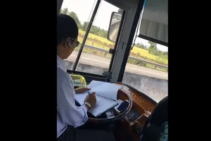Tài xế xe khách vừa lái xe vừa ghi chép sổ
