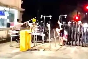 Người mang trang phục bảo vệ cầm gậy đánh nam thanh niên trước cổng ký túc xá làng đại học