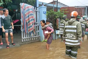 Một em bé được bà cõng ra khỏi vùng lũ tại quận Liên Chiểu. Ảnh: MINH TRƯỜNG.