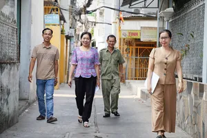 Bà Mai Thị Lệ, Trưởng khu phố 16, phường Bình Hưng Hòa A, quận Bình Tân (thứ hai từ trái sang) cùng cán bộ khu phố đi phổ biến kết quả sắp xếp khu phố, ấp đến người dân địa phương. Ảnh: THUẬN VĂN