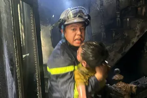Cảnh sát bế một em nhỏ thoát khỏi vụ cháy nhà ở Hà Nội