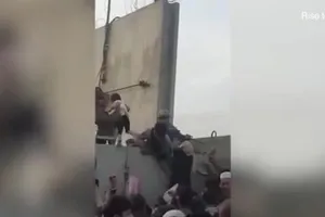 Một bé gái Afghanistan được nhấc qua bức tường cao và được đưa vào sân bay Kabul.
