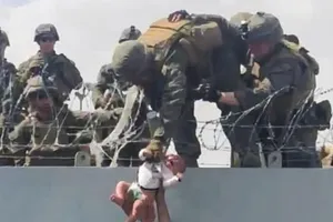 Một binh sĩ Mỹ kéo một đứa trẻ sơ sinh qua bức tường chắn tại sân bay Kabul.