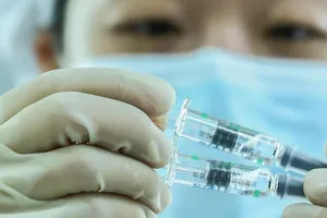 Một nhân viên y tế Trung Quốc cầm lọ chứa vaccine ngừa COVID-19.