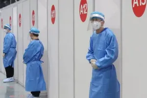 Nhân viên y tế đứng chờ bên ngoài trung tâm tiêm chủng ở Bắc Kinh, Trung Quốc, ngày 15-4.