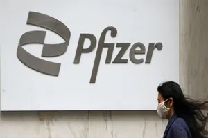 Một cô gái đi ngang qua logo tập đoàn dược phẩm Mỹ Pfizer ở thành phố New York, Mỹ, ngày 1-4. 