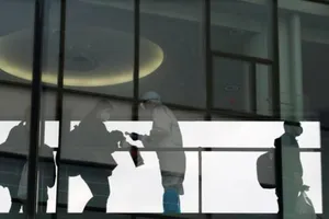 Nhân viên mặc đồ bảo hộ kiểm tra thân nhiệt các hành khách lên chuyến bay quốc tế tại sân bay quốc tế Narita ở Tokyo, Nhật Bản, ngày 30-11. 