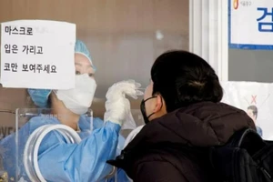 Nhân viên y tế lấy mẫu xét nghiệm COVID-19 từ một người đàn ông ở một nhà ga tại Seoul, ngày 8-12.
