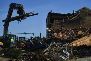 Công nhân dọn dẹp đống đổ nát của một tòa nhà sau khi cơn lốc xoáy quét qua tại bang Kentucky, Mỹ.