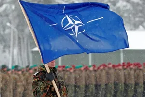 Một binh sĩ đang cầm cờ của Tổ chức Hiệp ước Bắc Đại Tây Dương.