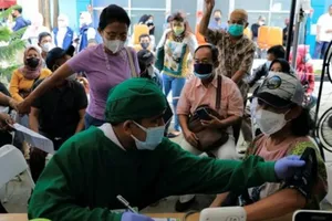 Nhân viên y tế thực hiện kiểm tra sức khỏe cho một phụ nữ trước khi tiêm mũi tăng cường ở Jakarta, Indonesia, ngày 12-1.