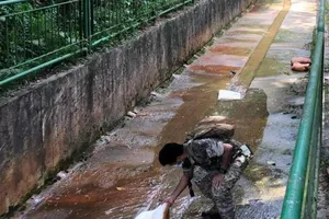 Một sĩ quan cảnh sát đang điều tra bên trong con kênh nơi tìm thấy xác của hai đứa trẻ.